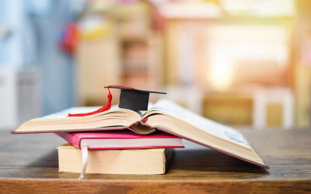 Education concept with graduation cap on a book on the wooden table background